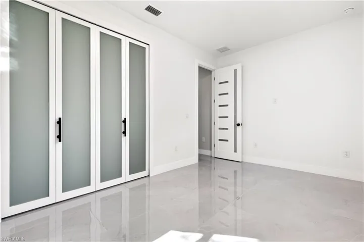 Unfurnished bedroom featuring baseboards and light marble finish flooring