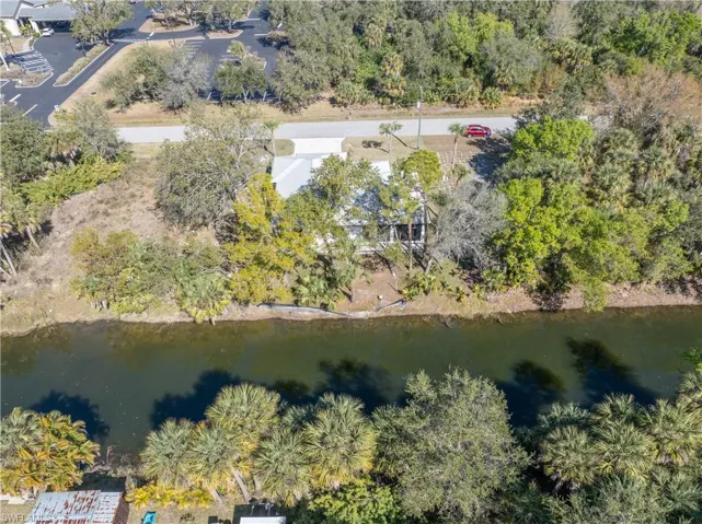 Aerial view of property and surrounding area with a tree filled landscape and a nearby body of water