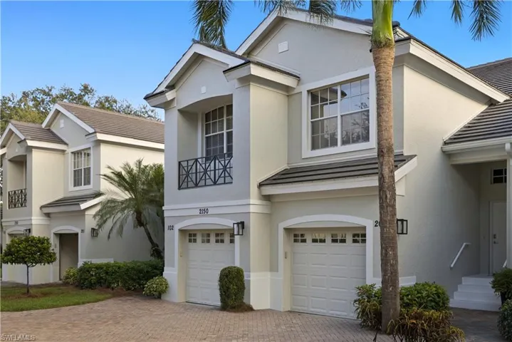 View of front of property featuring an attached garage, decorative driveway, stucco siding, and a balcony