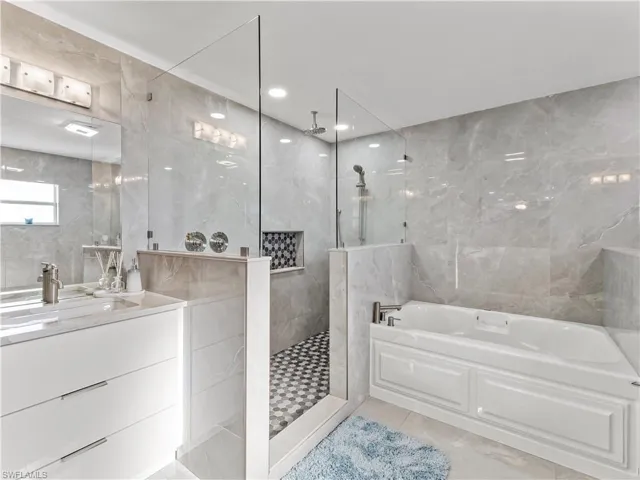 Full bath featuring tile walls, vanity, a bath, a walk in shower, and light tile patterned flooring