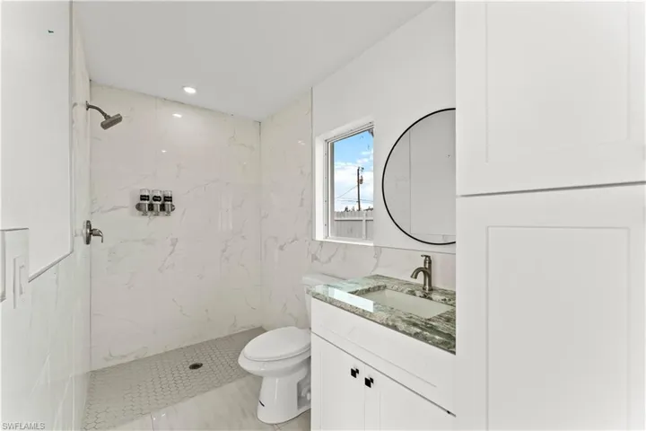 Bathroom featuring a marble finish shower and vanity