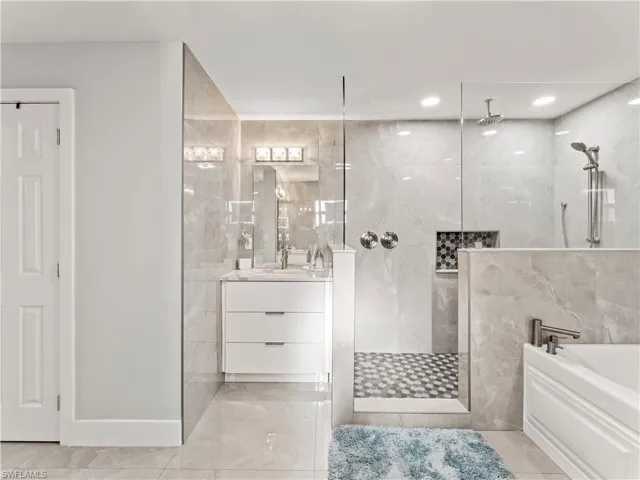Full bathroom with vanity, a garden tub, a marble finish shower, and light tile patterned flooring