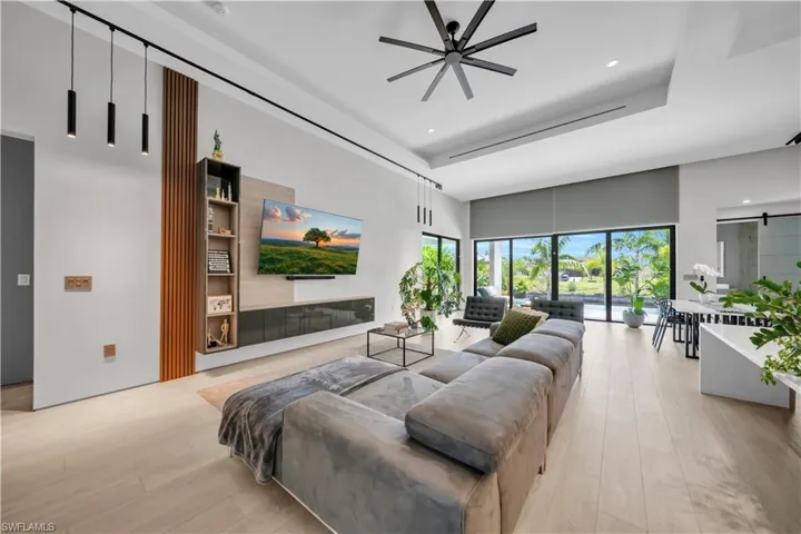 Spacious open-concept living area featuring light wood-finish flooring, a contemporary ceiling fan, and recessed lighting