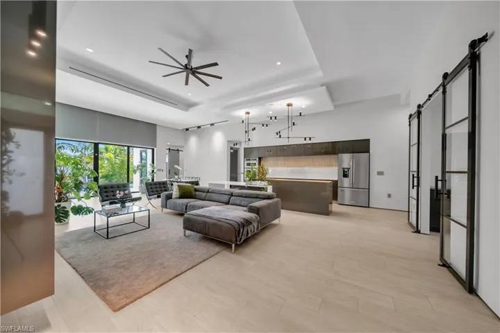 Open-concept living area featuring light wood-finish flooring and a tray ceiling