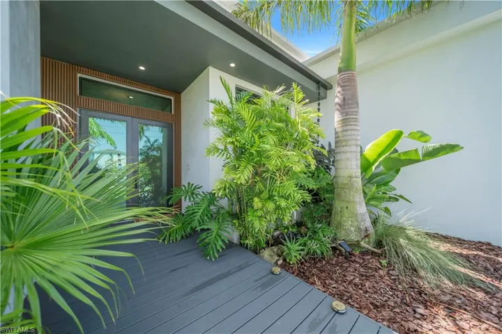 Entryway featuring a dark composite decking path leading to double glass doors with transom windows