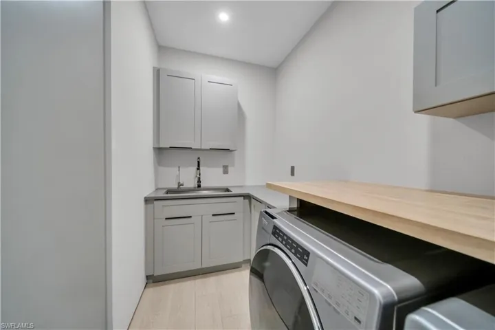 Dedicated laundry area featuring light wood-finish flooring