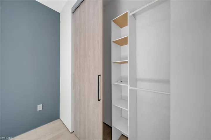 Closet featuring a wood-finish barn door, black hardware, built-in shelving, and a hanging rod
