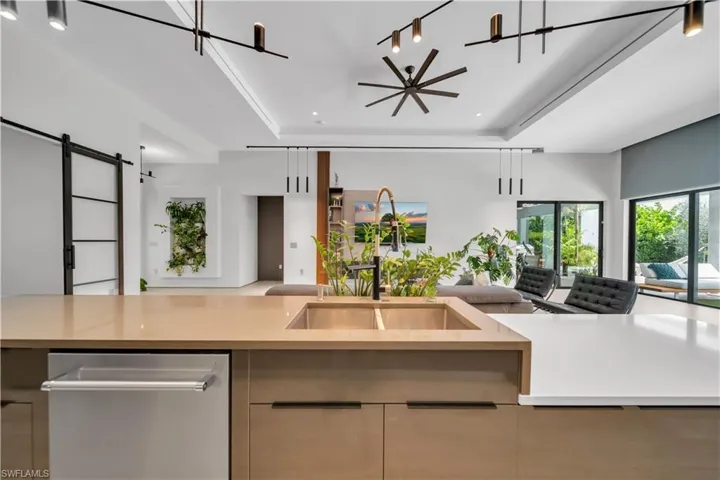 Contemporary kitchen island featuring a dual-basin sink, integrated dishwasher, and light-toned countertop