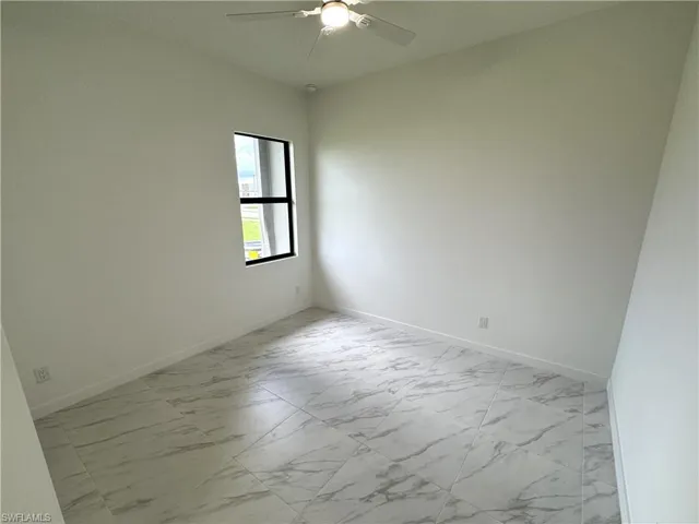 Empty room featuring light marble finish flooring and a ceiling fan