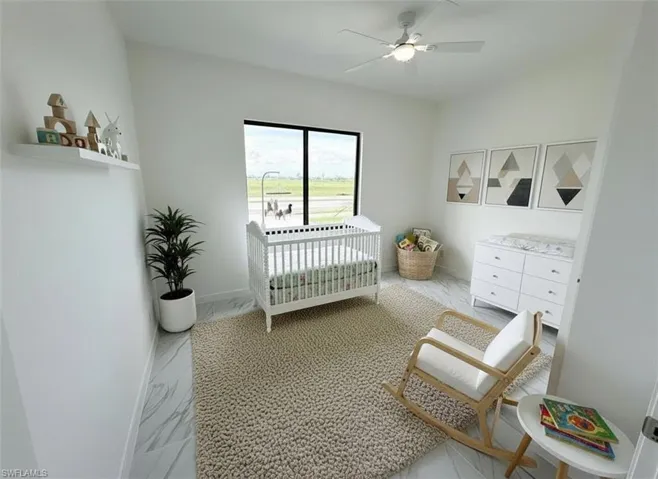 Bedroom with a nursery area, a ceiling fan, and light marble finish flooring
