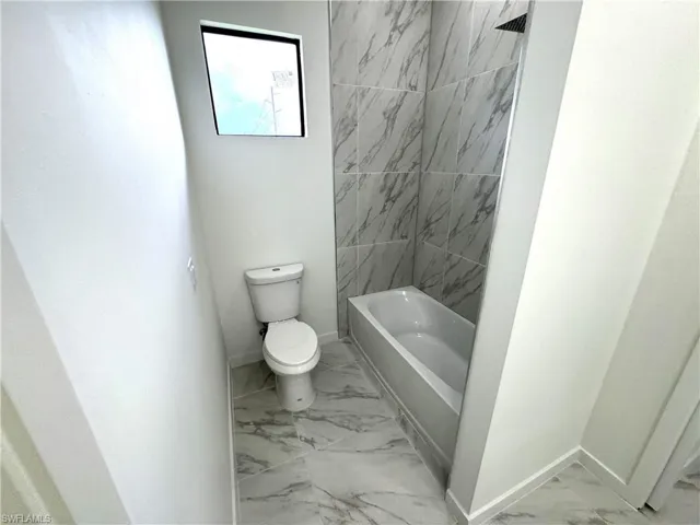 Full bathroom featuring light marble finish flooring and shower / washtub combination