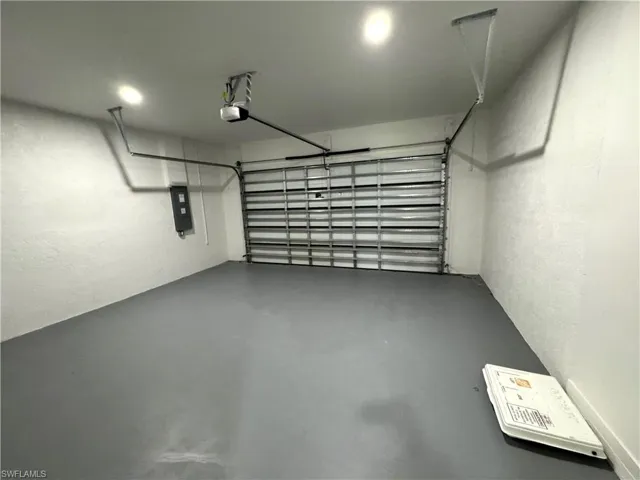 Garage with electric panel, a textured wall, and a garage door opener