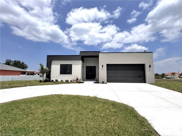 Contemporary house featuring driveway, stucco siding, and an attached garage