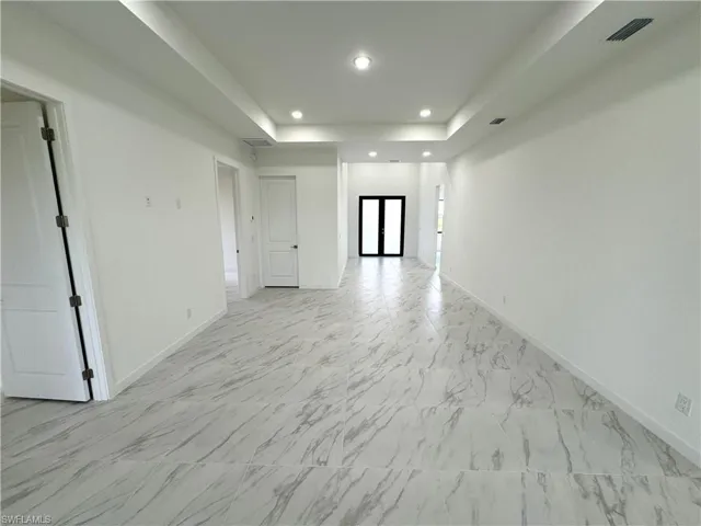 Unfurnished room featuring recessed lighting, a tray ceiling, and light marble finish floors