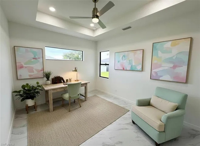 Home office featuring light marble finish flooring, a raised ceiling, recessed lighting, and a ceiling fan