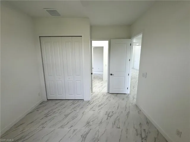 Unfurnished bedroom featuring light marble finish flooring and a closet