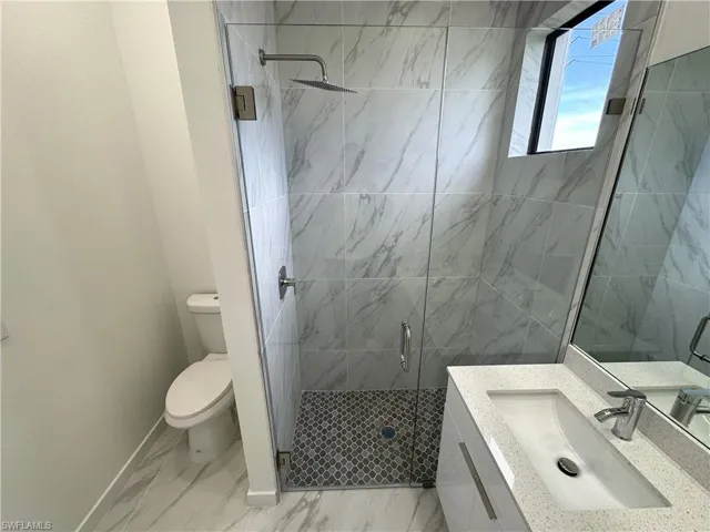 Bathroom with vanity, a stall shower, and light marble finish flooring