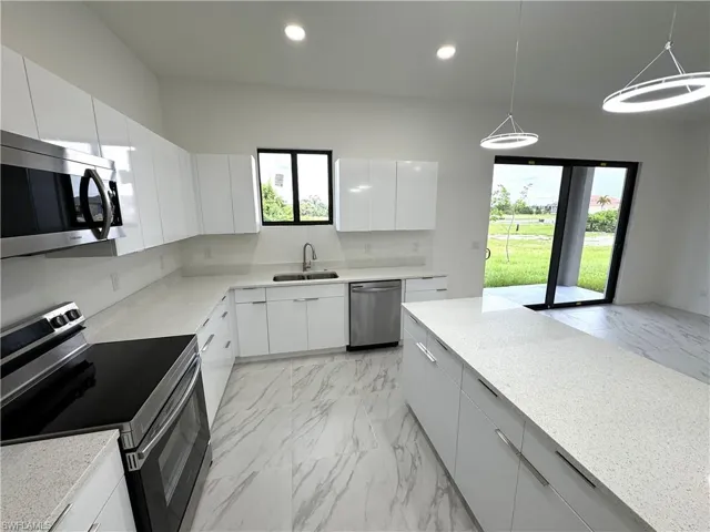 Kitchen featuring appliances with stainless steel finishes, modern cabinets, pendant lighting, healthy amount of natural light, and recessed lighting