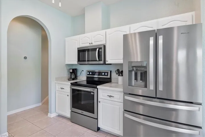 Kitchen with white cabinetry, stainless steel appliances, and light tile patterned flooring
