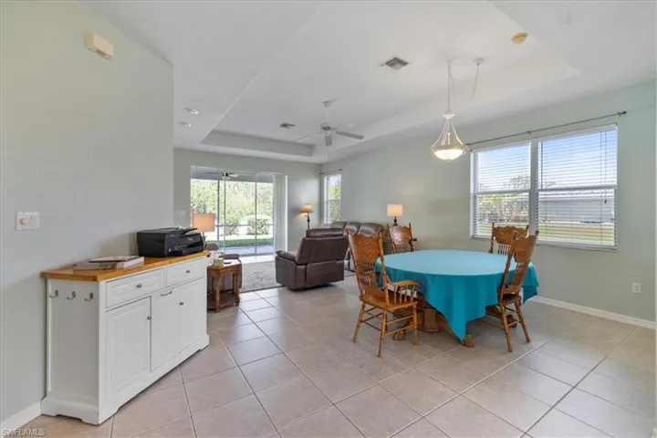 Dining area with ceiling fan, a raised ceiling, and light tile patterned floors