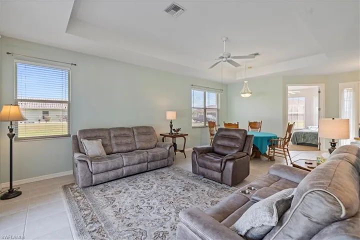 Tiled living room featuring a raised ceiling and ceiling fan