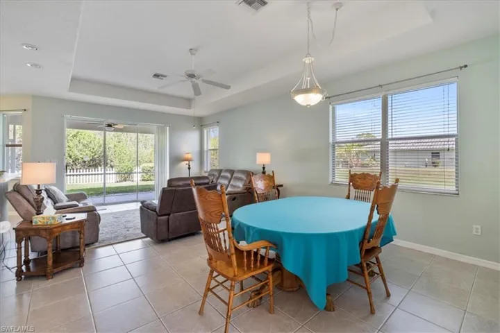 Tiled dining room featuring a tray ceiling and ceiling fan