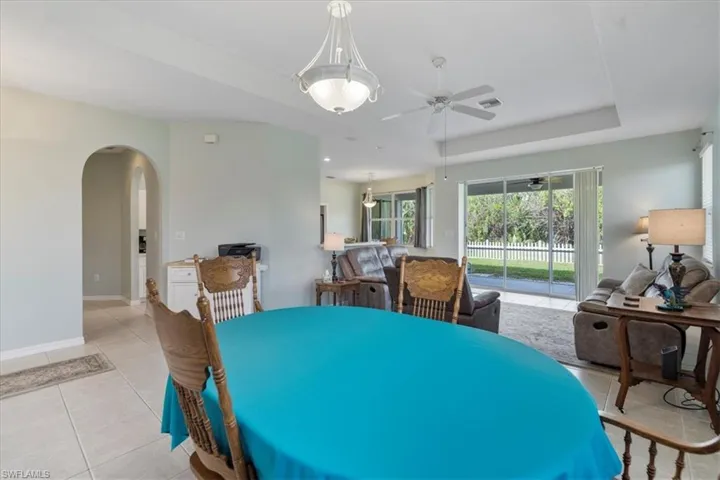 Tiled dining room featuring a raised ceiling and ceiling fan