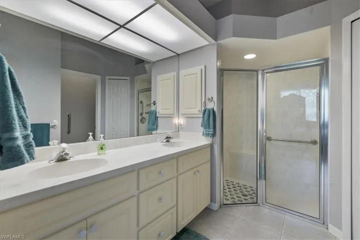 Bathroom featuring vanity, tile patterned flooring, and a shower with shower door
