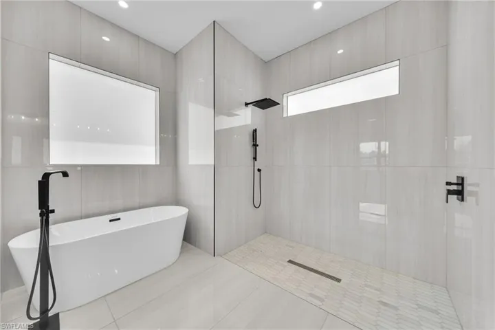 Bathroom featuring a freestanding tub, a walk in shower, tile patterned floors, and tile walls