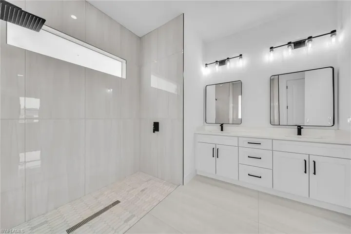 Full bath featuring double vanity, a tile shower, and tile patterned floors