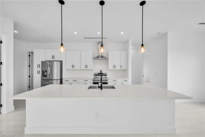 Kitchen with stainless steel appliances, white cabinetry, a large island, light countertops, and light tile patterned flooring