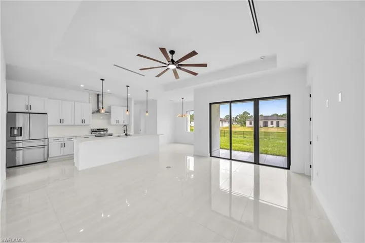 Unfurnished living room featuring a raised ceiling, light tile patterned flooring, and ceiling fan