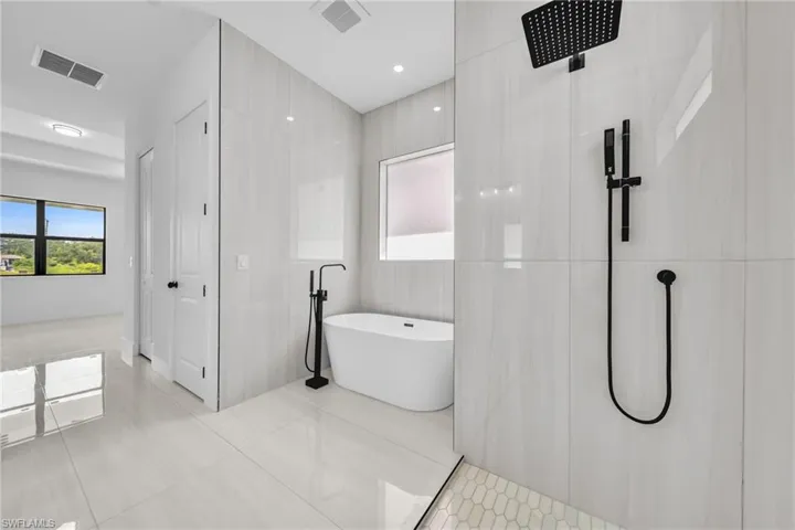 Bathroom with a freestanding tub, tile patterned floors, a shower, and tile walls