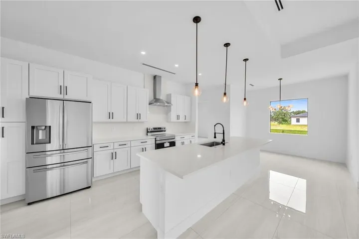 Kitchen featuring appliances with stainless steel finishes, wall chimney range hood, white cabinets, light countertops, and light tile patterned flooring