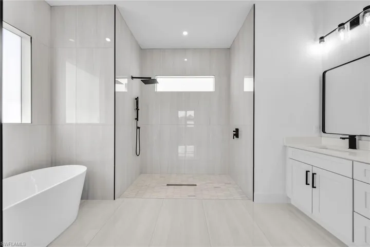 Full bath featuring a stall shower, a freestanding tub, and vanity