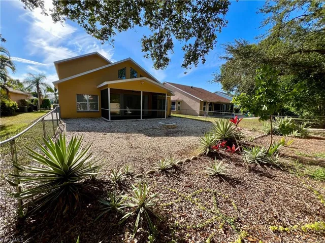 Rear view of house featuring stucco siding, a sunroom, and a fenced backyard
