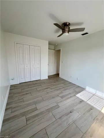 Unfurnished bedroom featuring wood tiled floors, ceiling fan, and a closet