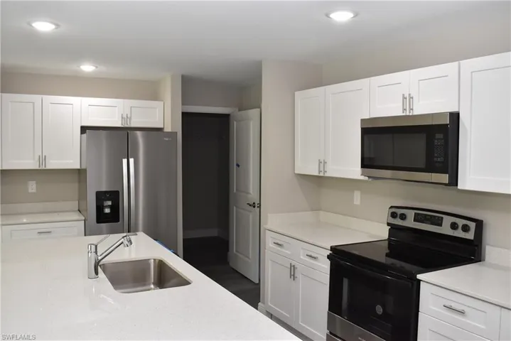 Kitchen featuring sink, white cabinetry, stainless steel appliances, and dark wood-type flooring