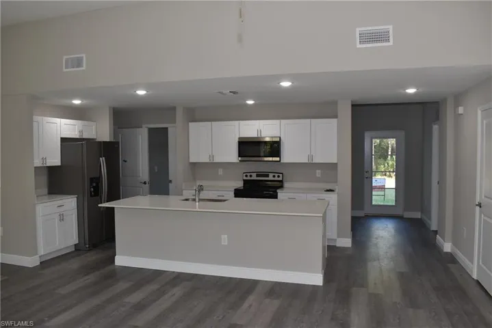 Kitchen with a center island with sink, white cabinetry, sink, and appliances with stainless steel finishes