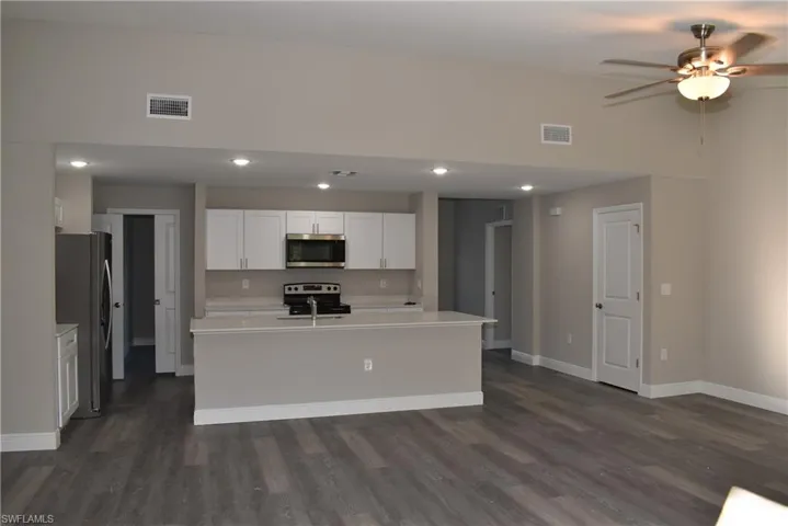 Kitchen featuring white cabinets, dark hardwood / wood-style floors, a kitchen island with sink, and appliances with stainless steel finishes