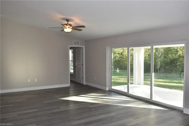 Unfurnished room featuring lofted ceiling, dark hardwood / wood-style flooring, ceiling fan, and a healthy amount of sunlight