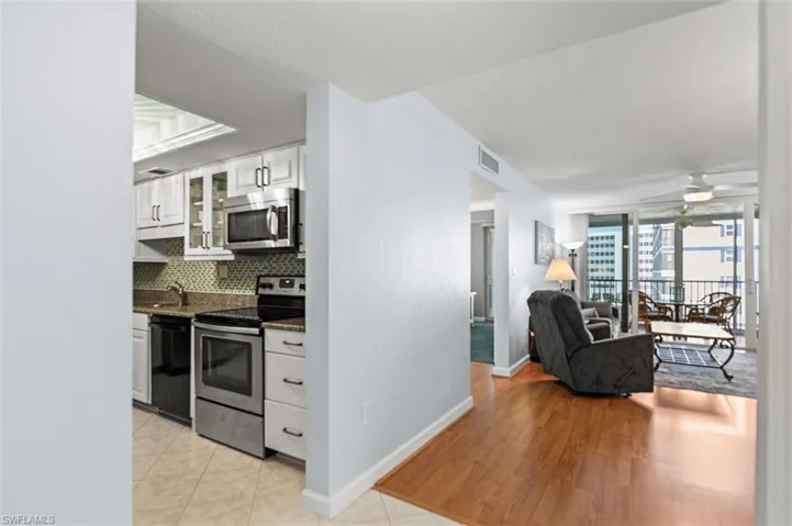 Kitchen with stainless steel appliances, white cabinets, dark stone counters, a ceiling fan, and open floor plan