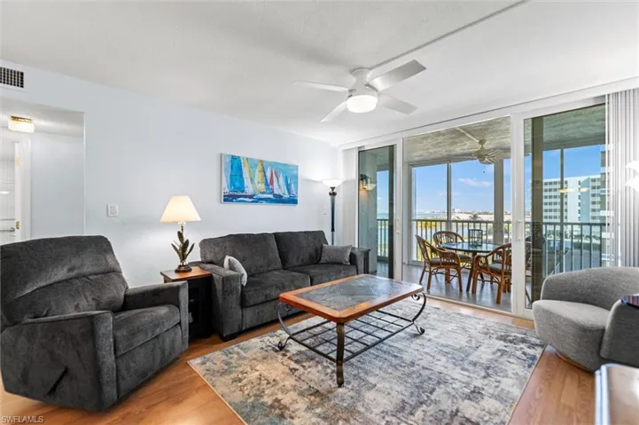 Living area with floor to ceiling windows, wood finished floors, a textured ceiling, and a ceiling fan