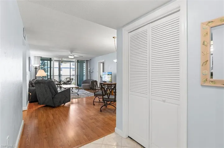 Living room with ceiling fan, light wood-type flooring, and a textured ceiling