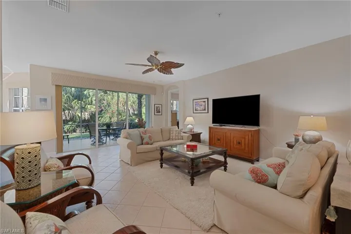 Living area featuring tile patterned floors, a ceiling fan, and arched walkways