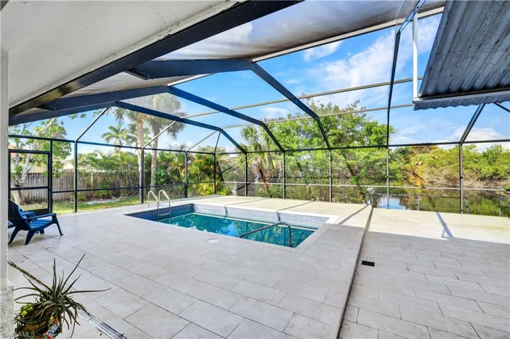 Swimming pool featuring a sunroom, a patio, and glass enclosure
