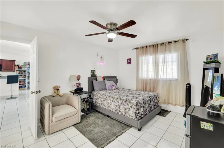 Bedroom with a ceiling fan, stainless steel fridge, and light tile patterned flooring