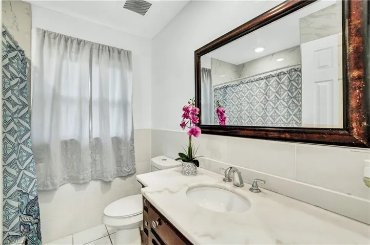 Bathroom with vanity, a shower with curtain, tile walls, and a wainscoted wall