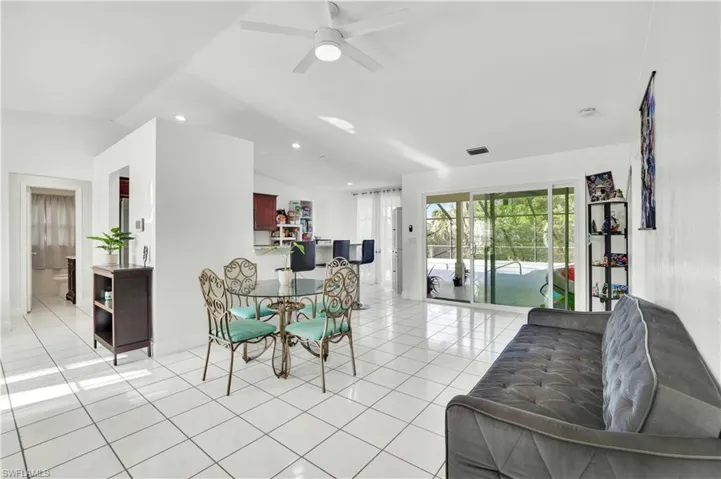 Dining area with light tile patterned floors, a ceiling fan, lofted ceiling, and recessed lighting