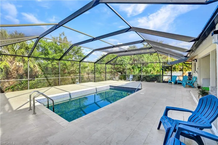 Swimming pool with a sunroom, a patio area, and glass enclosure